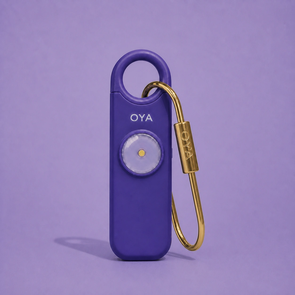 L’alarme personnelle OYA en Lilac Pearl avec son clip doré, sur un fond assorti à la teinte